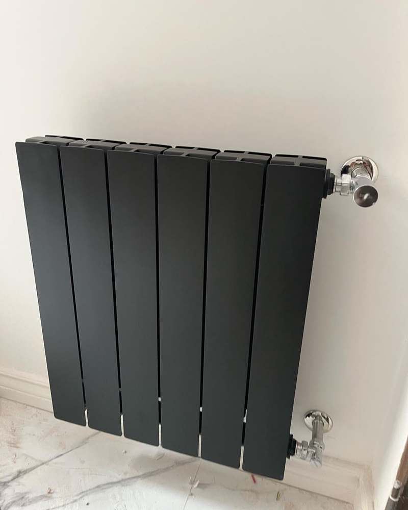 Radiador gris instalado con llaves de paso